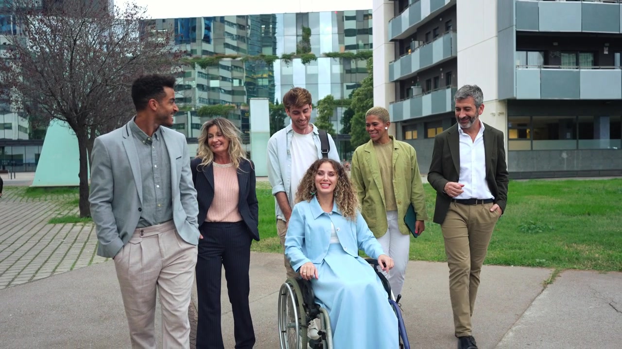 Diverse Group of Professionals Walking Together Outdoors with Colleague in Wheelchair