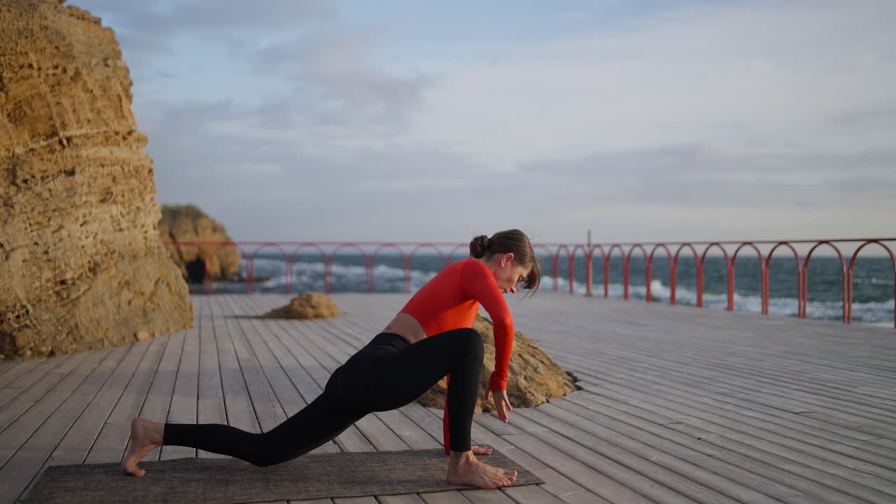 mujer practicando yoga en una cubierta de madera con vistas al océano