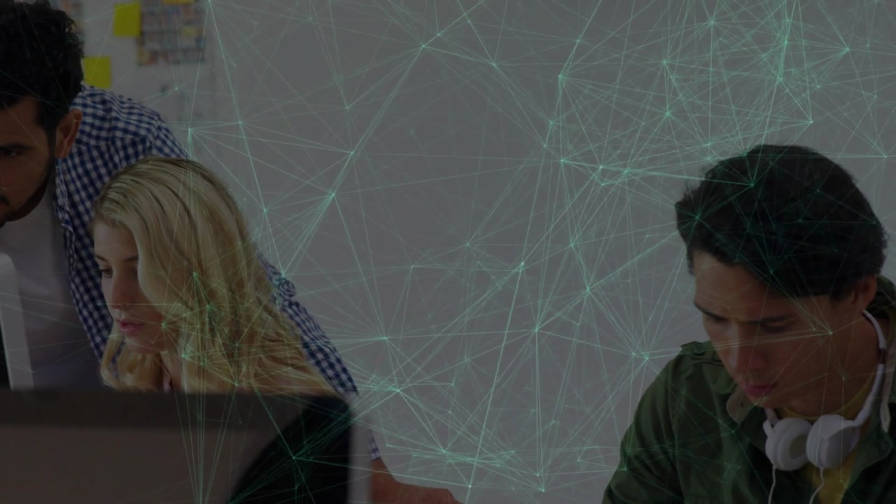 Mid-career colleague entering and leaning guiding coworker typing with technology network lines