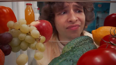 frustrated person looking at food in refrigerator