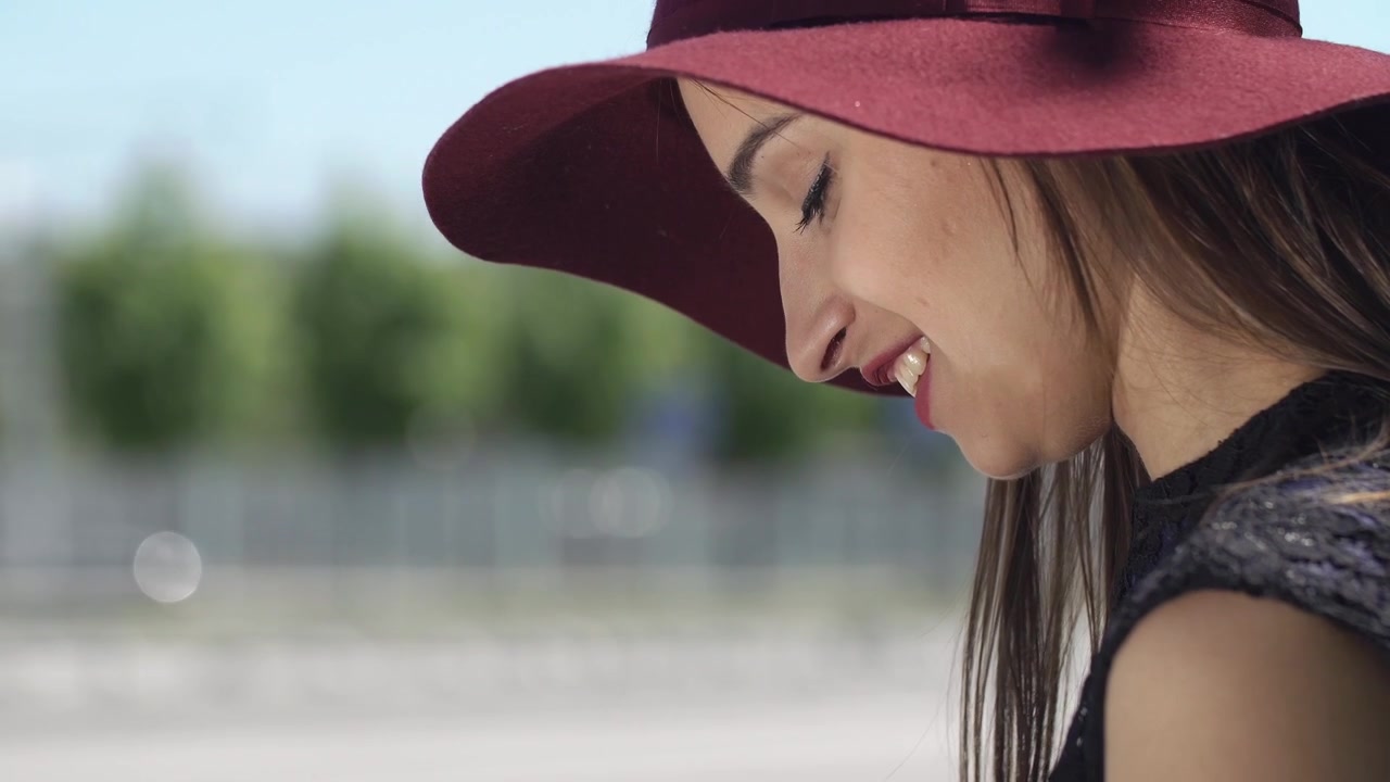 Giovane donna con cappello che sorride e digita sullo smartphone