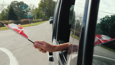 hand holds canada flag out of car window