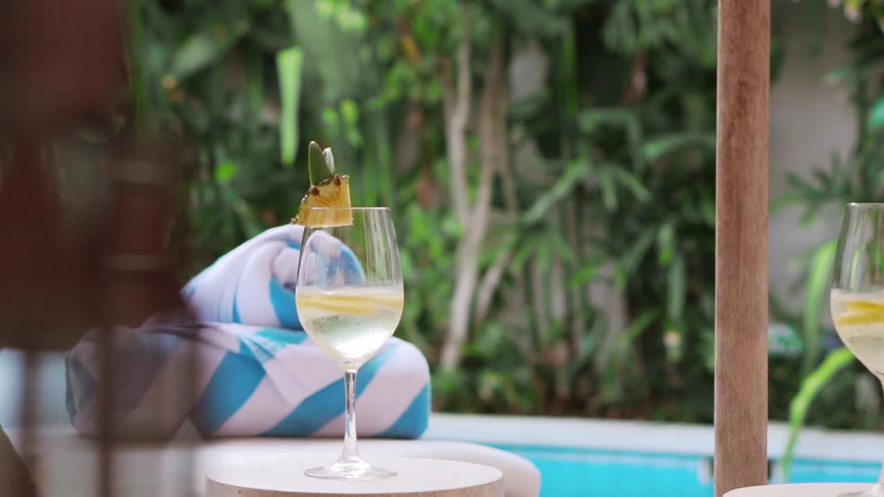 panorámica lenta alrededor del área de la piscina de la villa con toallas y bebidas heladas