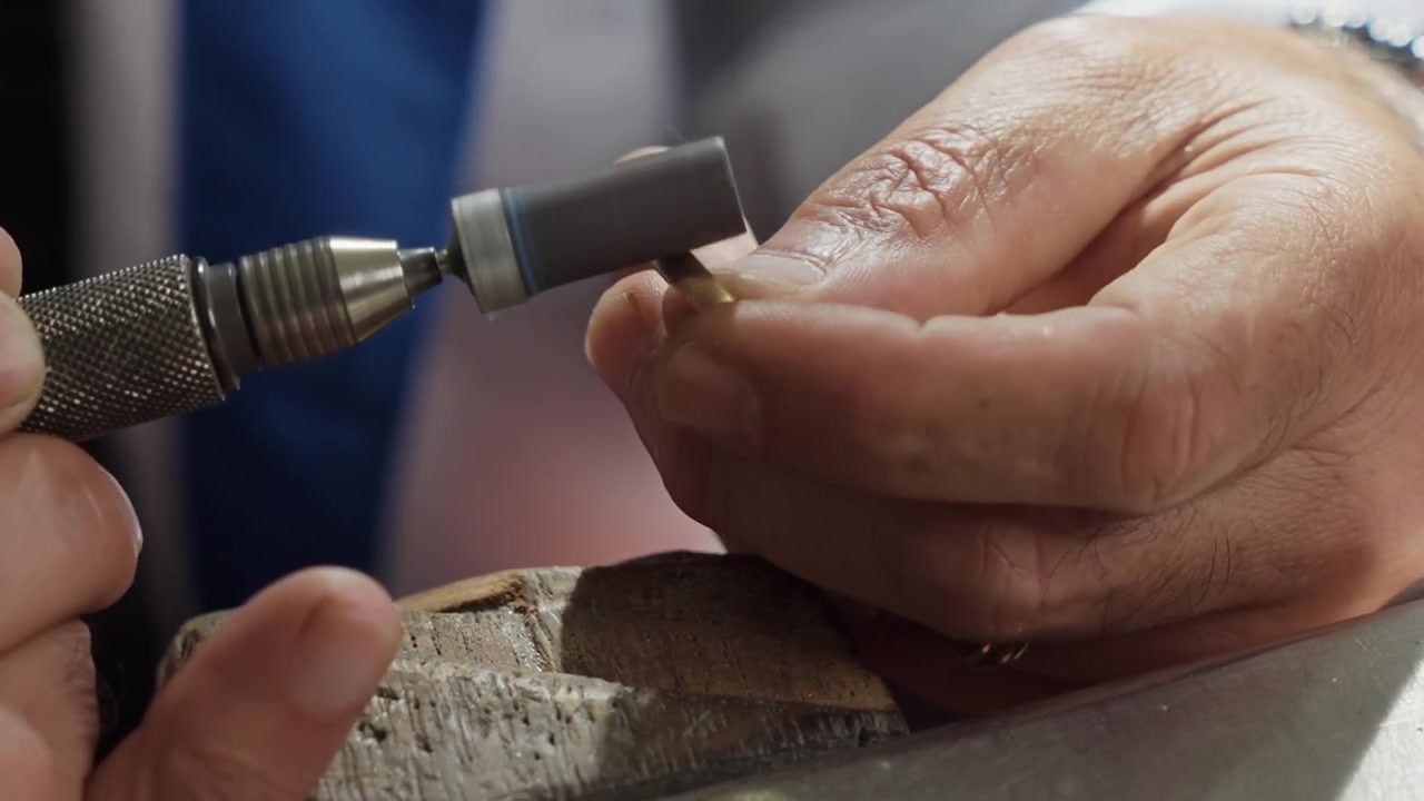 Jeweler hands polishing gold wedding ring with rotary buffing tool close up in workshop