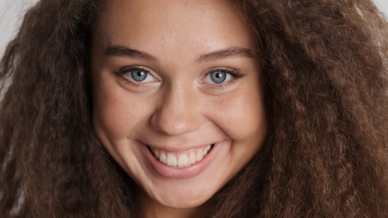 una mujer caucásica de cabello rizado sonriendo a camara.