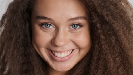 caucasian curly haired woman smiling to camara.