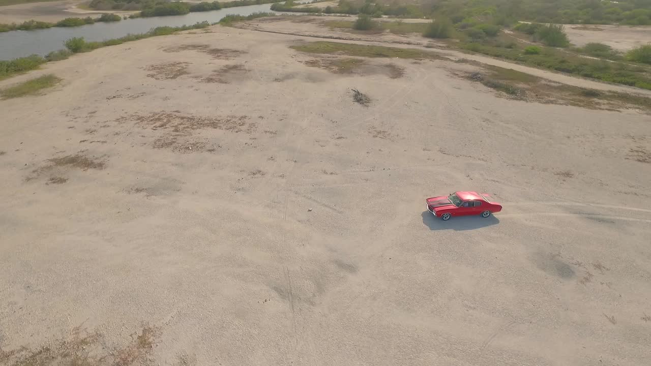 vista aérea de un viejo coche muscular americano en un desierto durante una puesta de sol