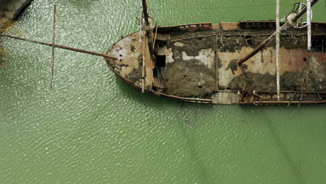 Rusty-red-shipwreck-stuck-in-shallow-green-water