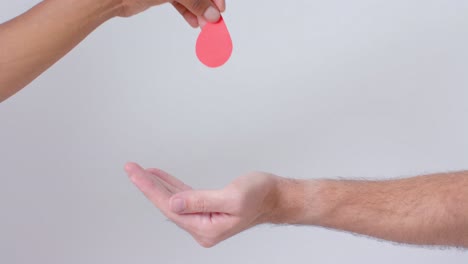 hands of diverse people giving blood drop on white background, slow motion