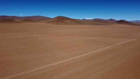 aerial rotates to reveal rough road on altiplano desert sand, bolivia