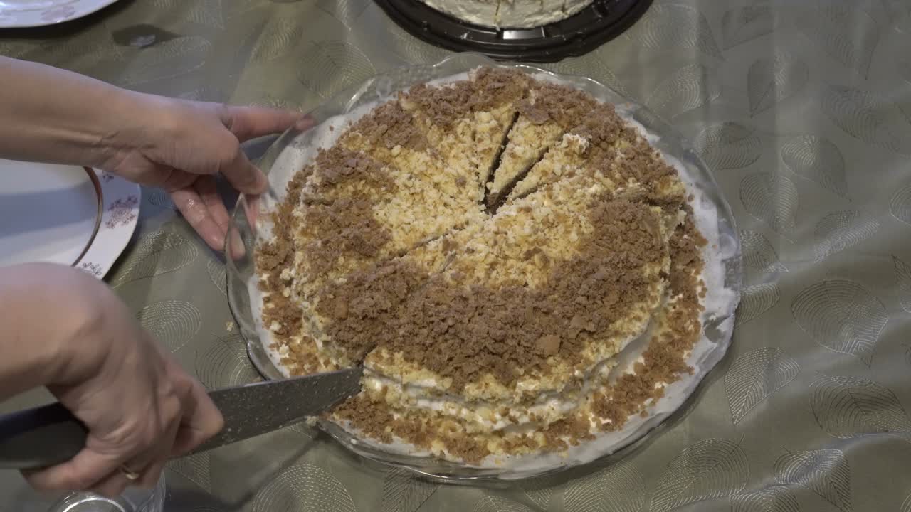A woman cuts a brown homemade cake with a large kitchen knife. The concept of a home holiday. Close up. Faceless. The view from the top. 4K.