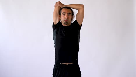 hispanic man with long hair and goatee performing tricep stretch against white studio backdrop