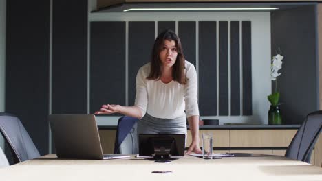 Caucasian-businesswoman-talking-on-video-call-in-conference-room-in-modern-office