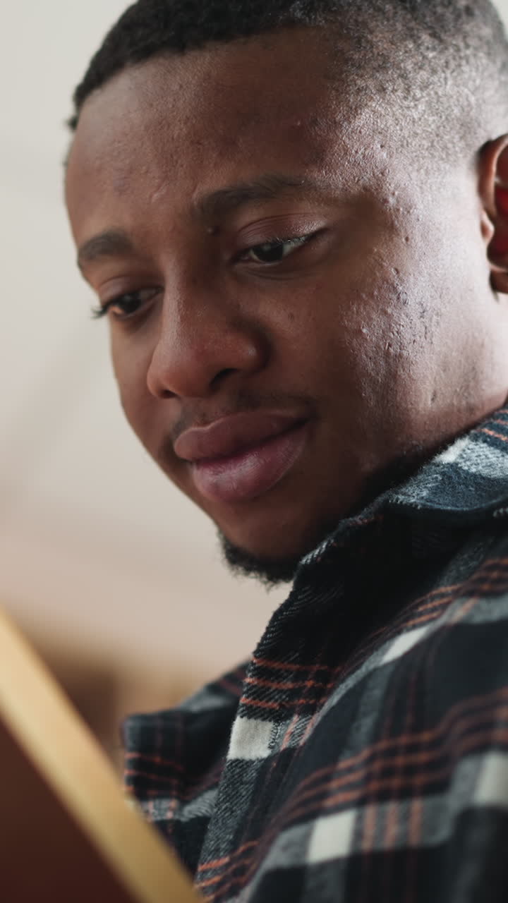 Dark-skinned man learns literature in library. College student reads educational literature in campus bookstore as part of exam preparation. Guy reads story