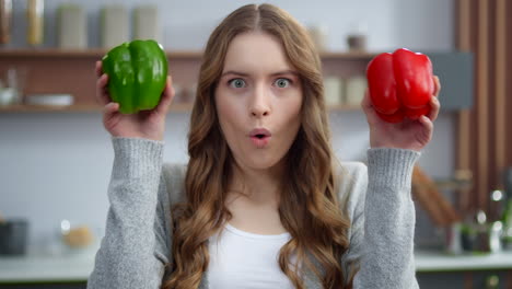 Portrait-of-young-woman-changing-emotions-with-colorful-peppers-at-home-kitchen.