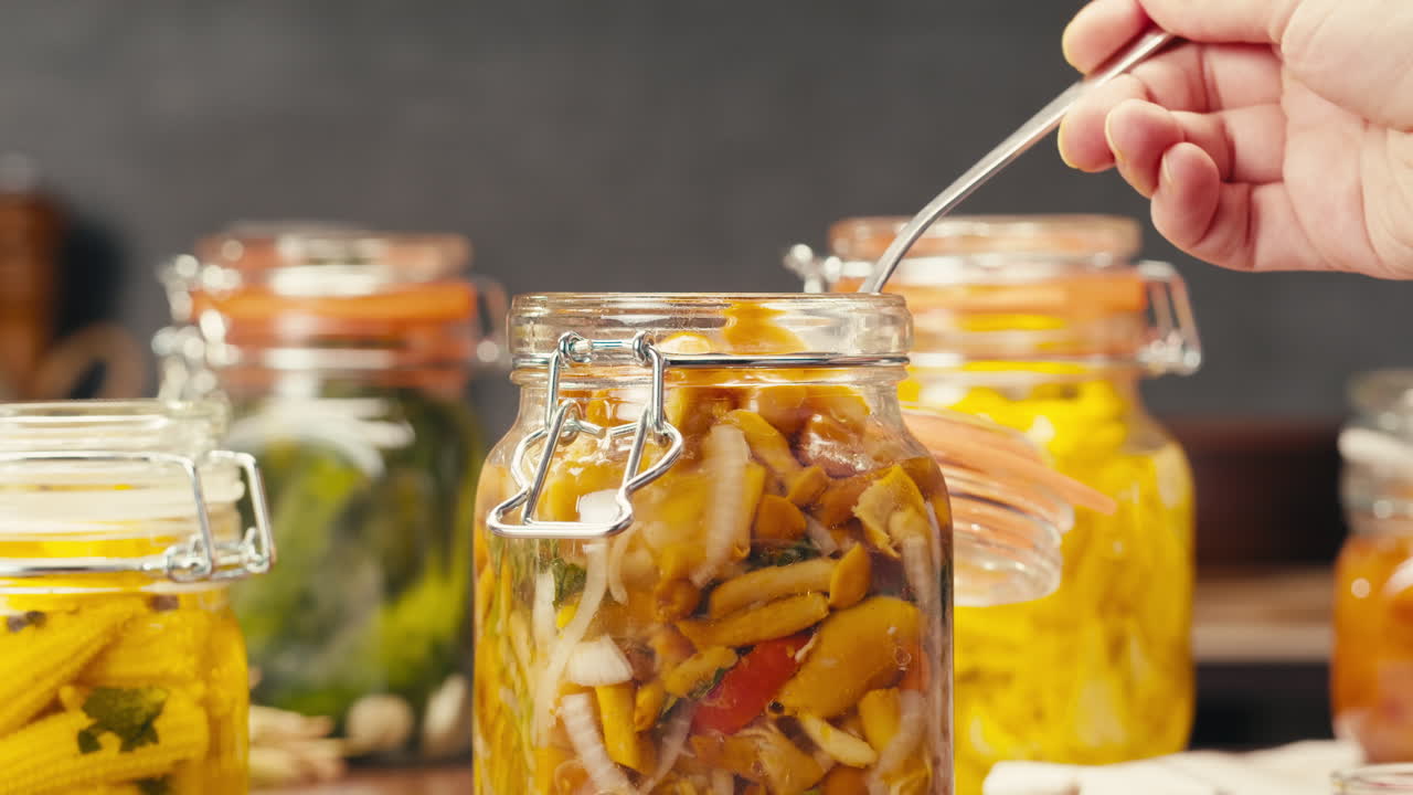 Fermented food in glass cans on table close-up. Preservation of vegetables in glass jars. Fermentation preserved mini corns, kimchi, cucumbers, mushrooms with spices.