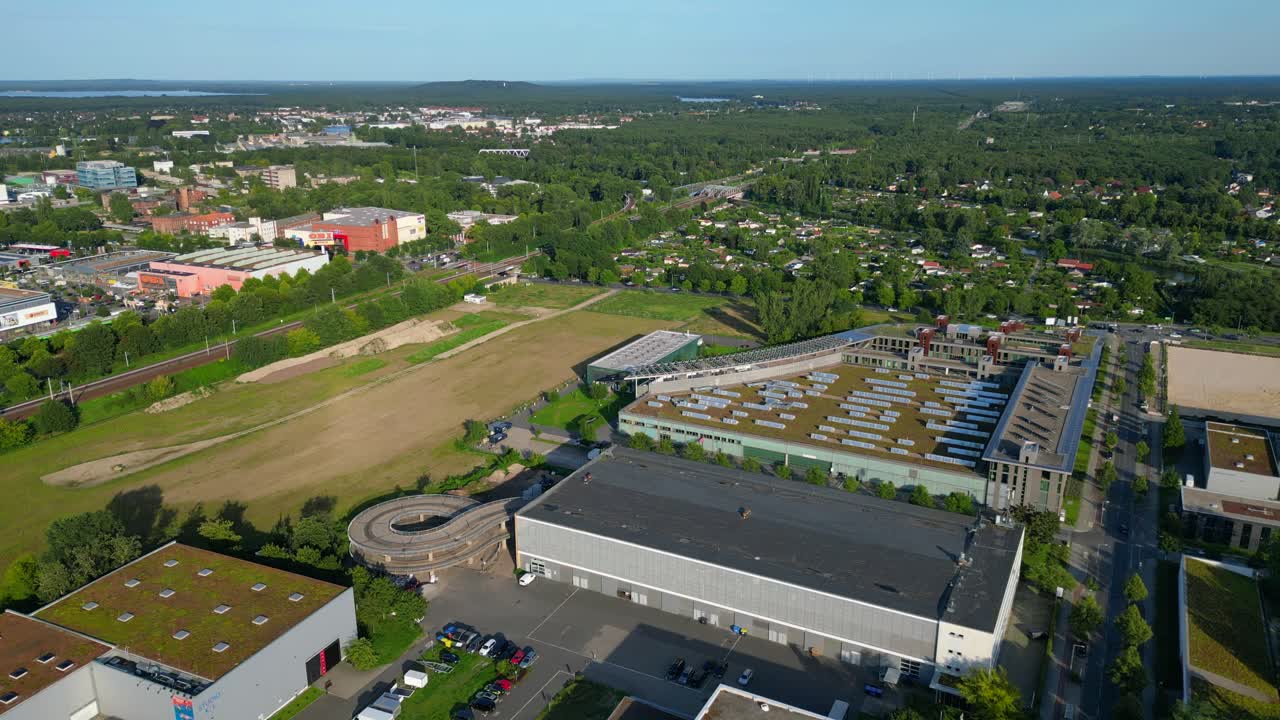 Modern film studios with offices and sound stages surrounded by trees in Berlin Adlershof, Germany. Smooth aerial view flight drone shot from above
