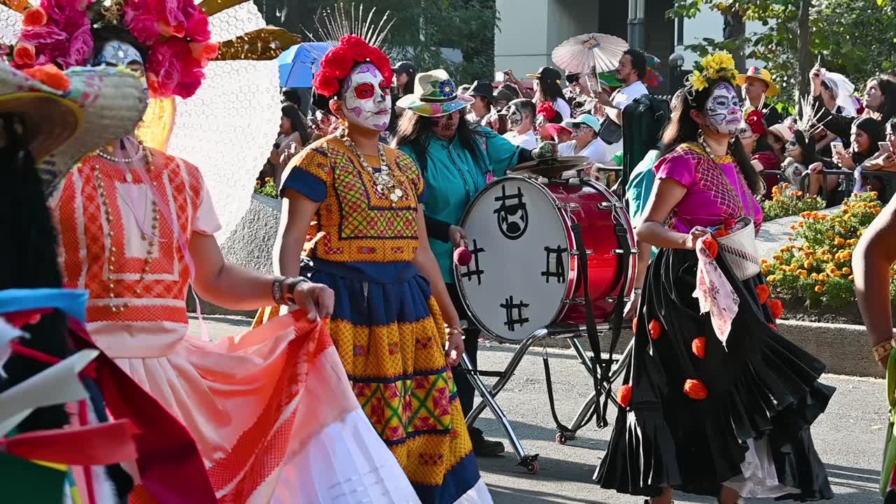 Vibrant Day of the Dead parade with performers dancing in traditional attire highlighting mexican culture