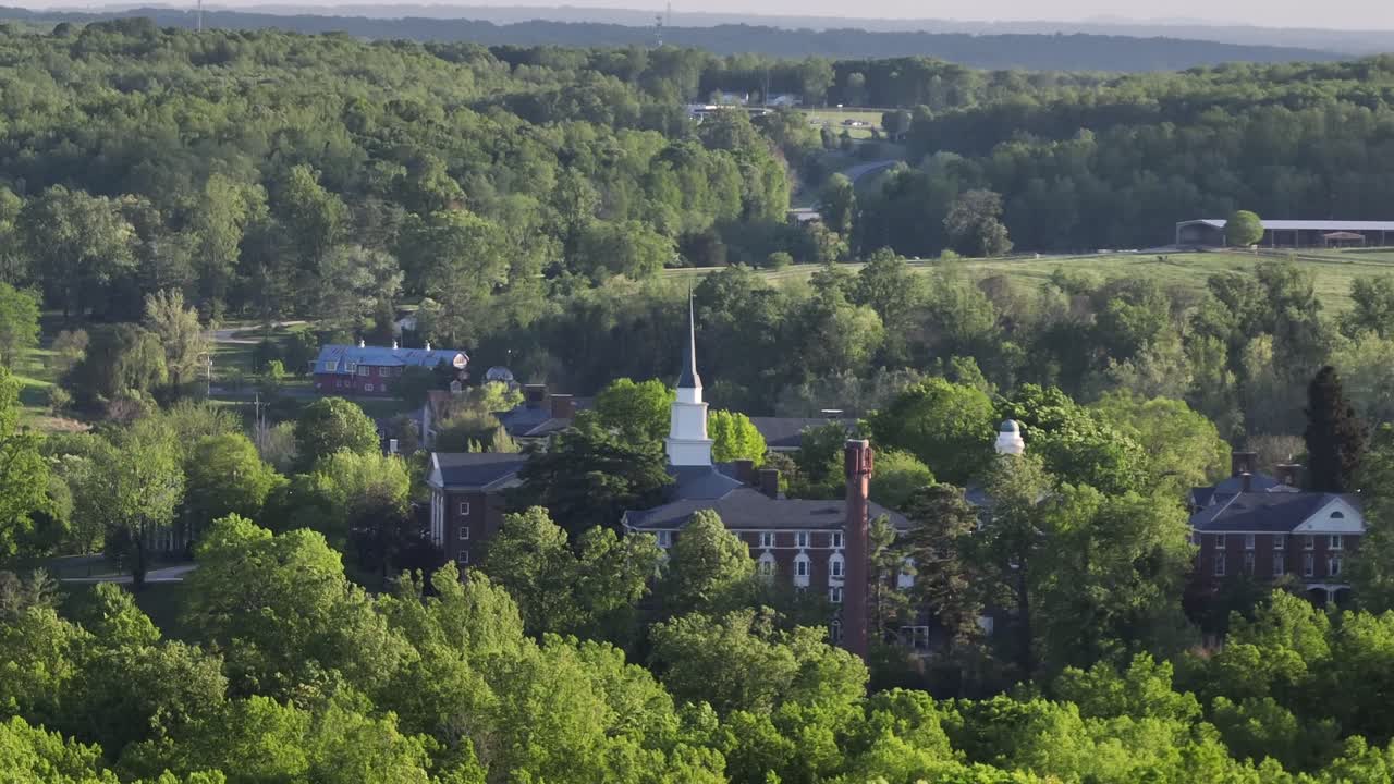 Sweet Briar College with church tower with green trees at sunset. Aerial approaching shot. Lynchburg Town, Virginia.