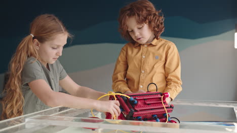 pair of kids putting plastic robo boat into water