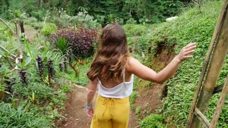 a young attractive woman is walking on a path outdoor with a calm and peaceful surrounding of plants, trees and a scenic view