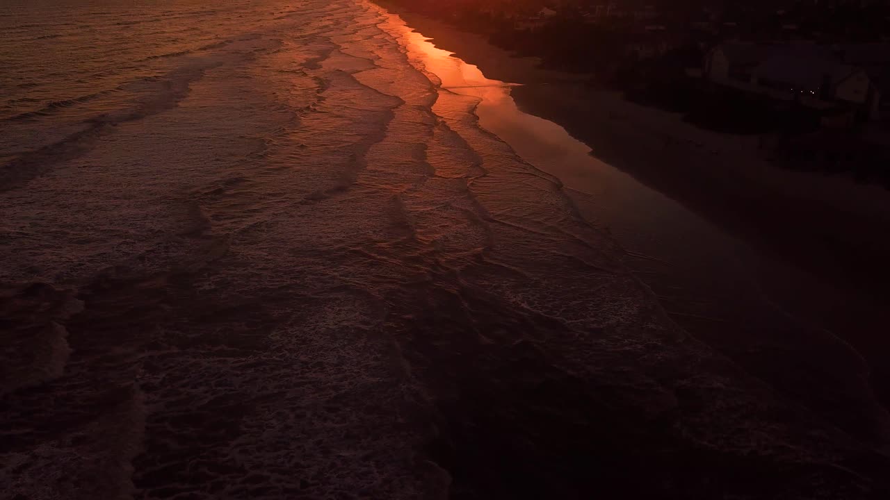 toma aérea de una playa vacía que muestra un hermoso atardecer