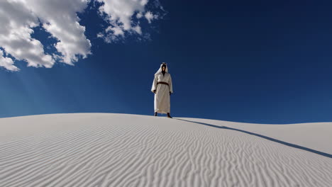 man in traditional garb on a white sand dune