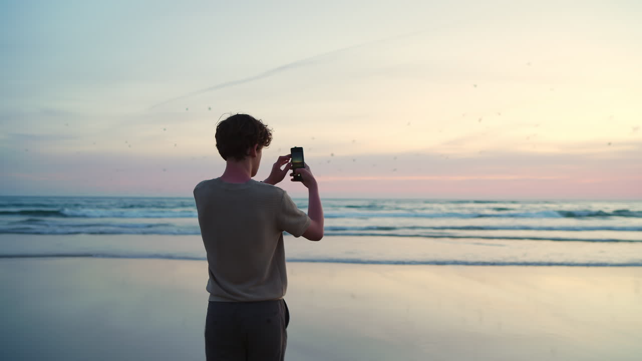 Young Man Taking Photos of Sunset on a Serene Beach