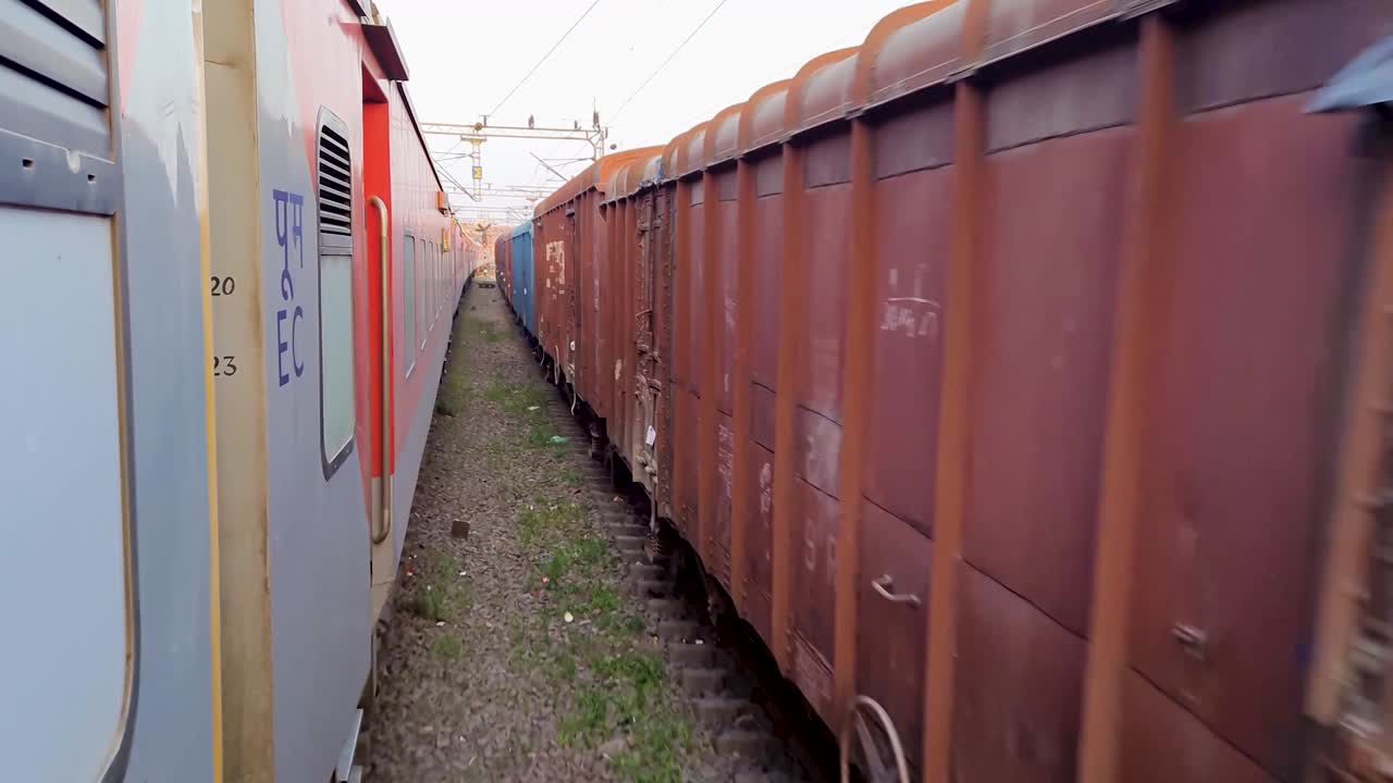 el tren de pasajeros que circula por la vía cruza el tren de mercancías desde la dirección opuesta por la mañana. el video se toma en la estación de tren de nueva delhi el 04 de agosto de 2022