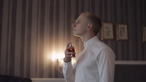 el novio se coloca perfume o desodorante en sí mismo, día de la boda, cámara lenta, hombre de negocios bien vestido