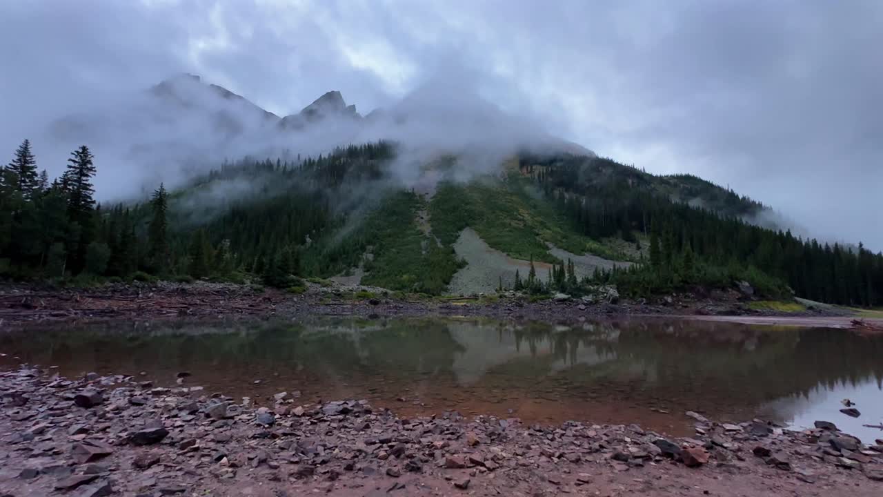 Early morning wet rainy cloudy foggy sunrise Crater Lake Maroon Bells Wilderness Aspen Snowmass fourteener peaks Colorado Rocky Mountains nature panora summer alpine backcountry hike trail pan left
