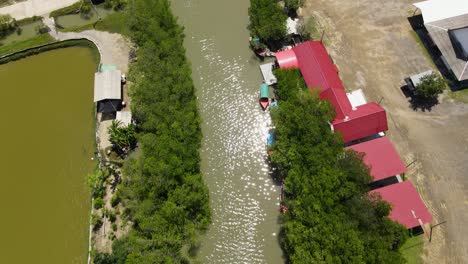 Aerial-footage-showing-red-roofs,-saltpans-and-fishponds,-the-river,-touring-boats,-and-the-bridge