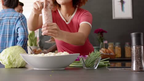 un grupo feliz y diverso de amigos preparando la comida en la cocina, cámara lenta
