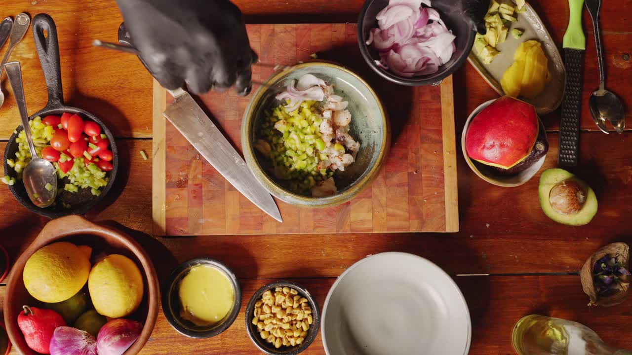 preparación de ceviche - vista de mesa de un chef hábil agregando cebollas rojas frescas y vertiendo aceite de oliva en un tazón de ingredientes, preparándose para el aperitivo tradicional peruano, concepto de escena culinaria