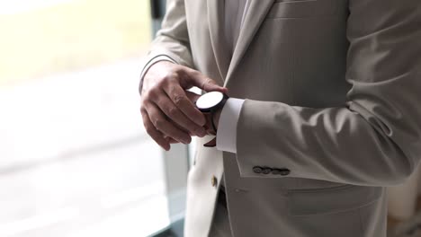 Elegant-gentleman-businessman-in-a-suit-tuxedo-adjusting-classic-brown-wristwatch