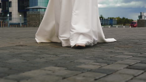 una novia elegante en vestido de novia camina hacia el novio a lo largo de la plaza