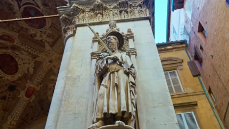 Eine-Statue-Schmückt-Eine-Säule-Der-Kaufmannsloge,-Loggia-Della-Merchandise,-Die-Sich-Hinter-Der-Piazza-Del-Campo-In-Siena,-Italien,-Befindet