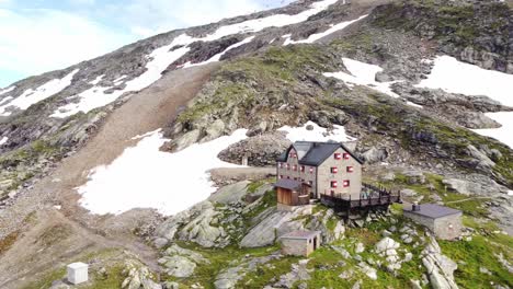 house surrounded by stones and a few snow field with a rope way in the background in the alps in kaernten, austria