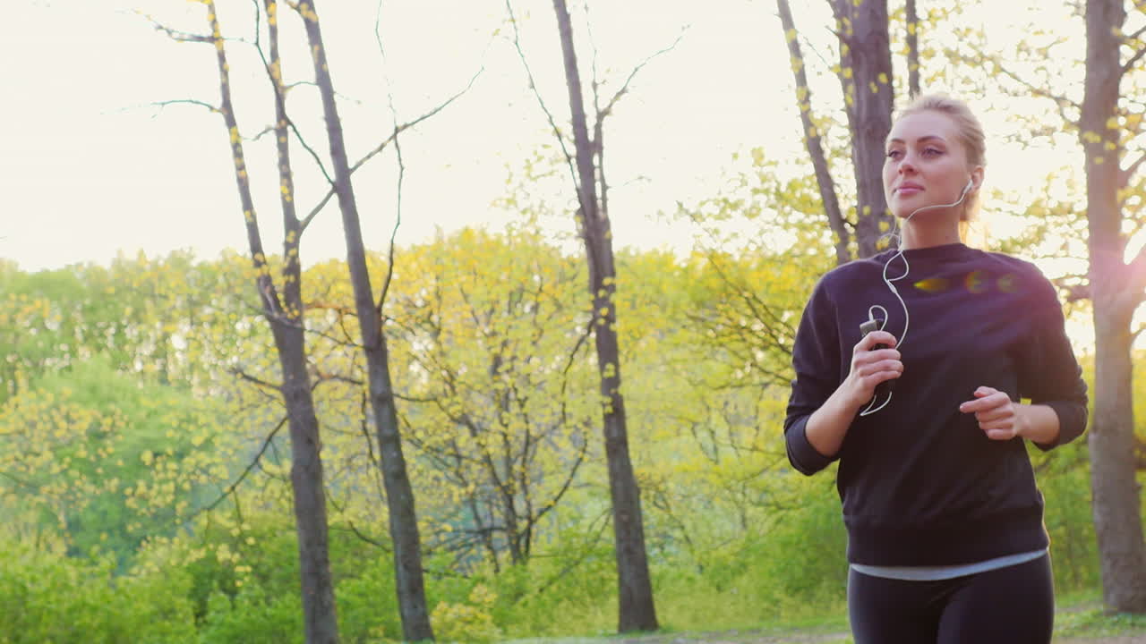 una joven atractiva hace un trote matutino en el bosque el sol brilla maravillosamente y da