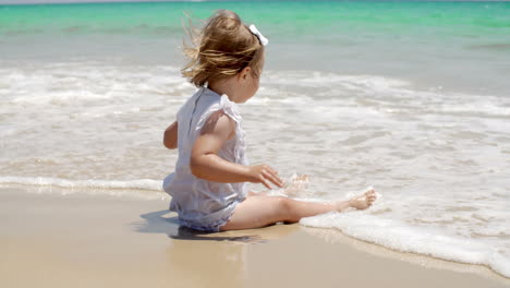 Süßes-Babymädchen-Sitzt-Am-Strand