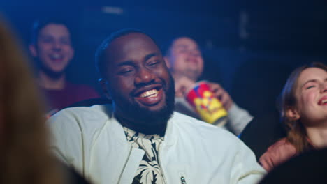 african man eating popcorn in movie theater