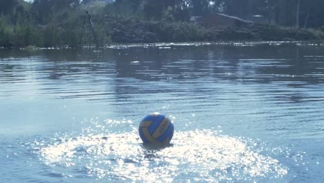 polo ball hitting shimmering water on dam in slow motion