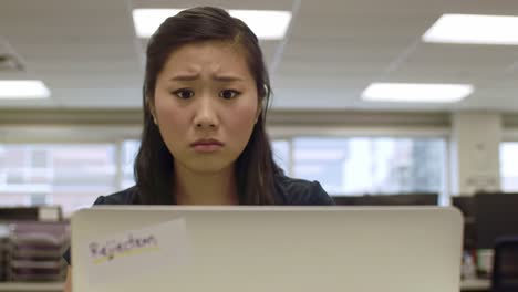 individual struggles with feelings of disappointment and anxiety after receiving multiple job rejections in a busy office environment. the surroundings reflect a typical workday atmosphere.