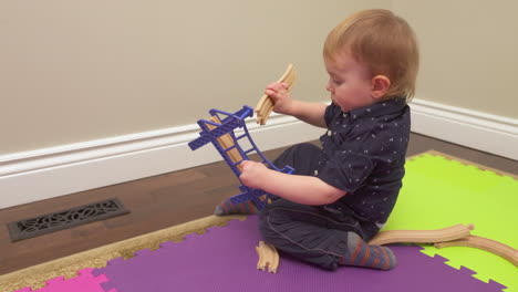 Baby-boy-trying-to-put-a-toy-train-track-together