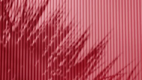shadow of palm leaves on vertical red corrugated metal wall. abstract natural light and line pattern background. design for wallpaper, banner, postcard, greeting card, poster, vertical