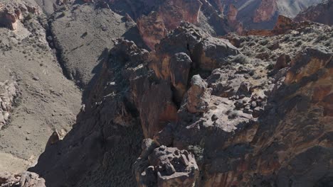 drone slow fly through rock formations at leslie gulch oregon and tilt down to reveal birds and a windy dirt road