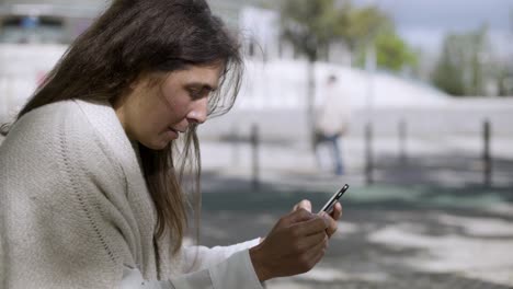 una mujer de mediana edad escribiendo el número de la tarjeta en su teléfono inteligente.