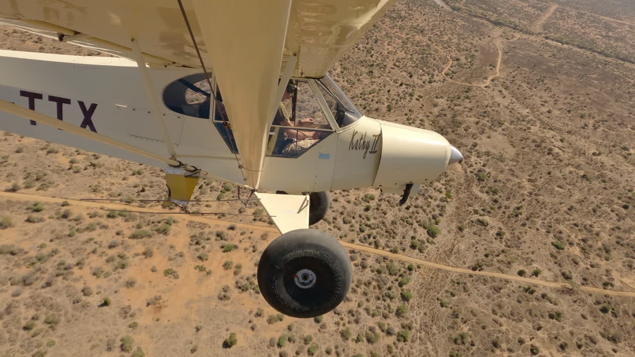 Piccolo aereo bushcraft in volo su una strada sterrata e un letto di fiume