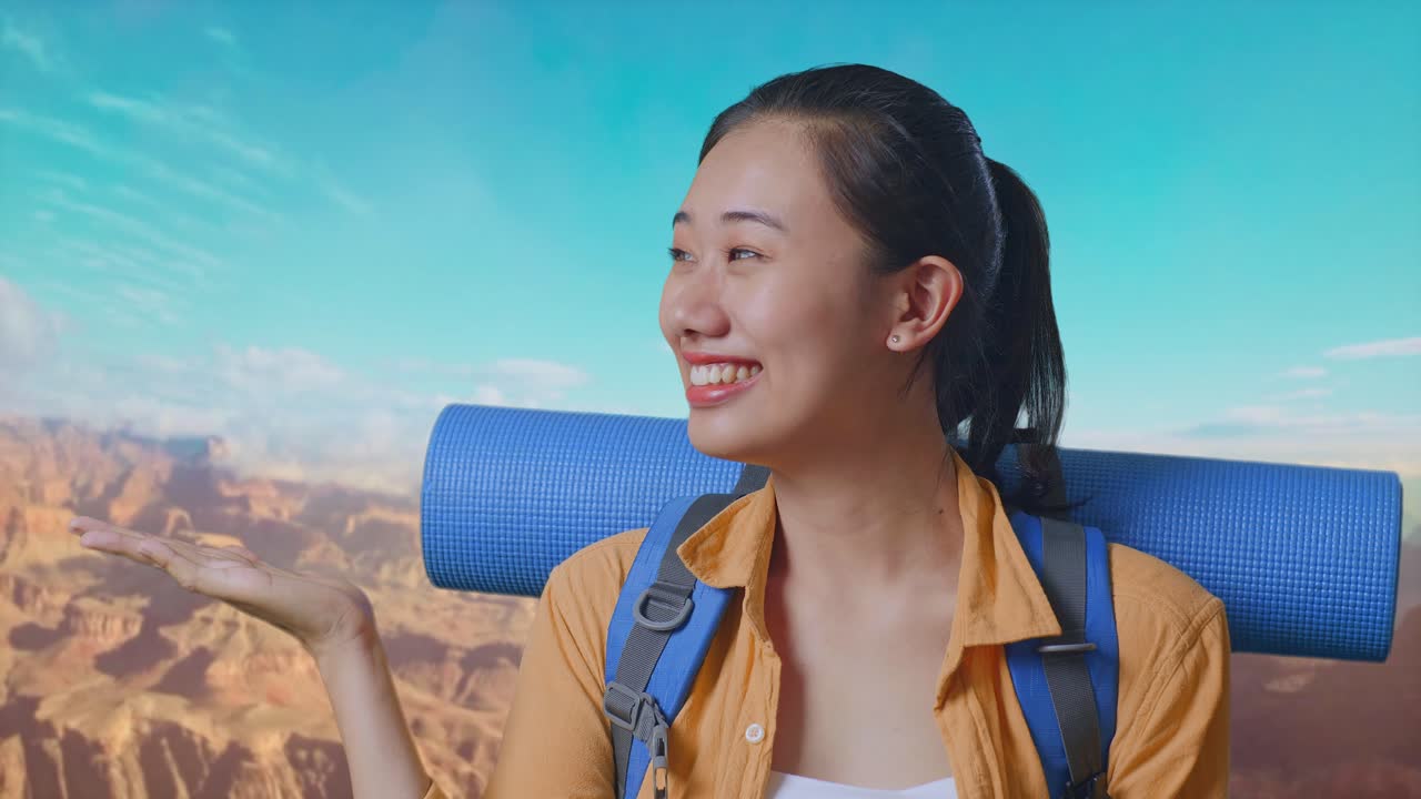 Close Up Of Asian Female Hiker With Mountaineering Backpack Smiling And Pointing To Side While Traveling At The Top Of Mountain