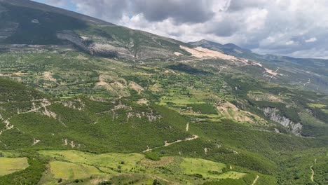 Aerial-shot-of-mountain-with-forest-and-fields-with-eroded-mountainside-on-a-cloudy-day